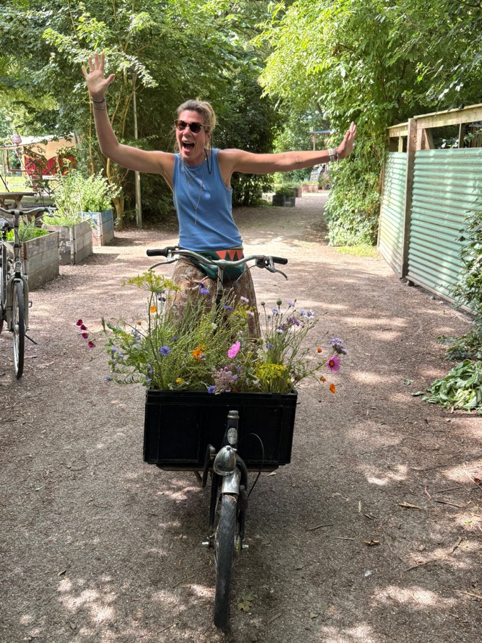 Gerdien op de bakfiets vol bloemen, armen omhoog
